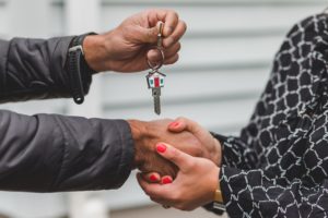 Close view on woman's hand hold man's hand as he passes her house keys.