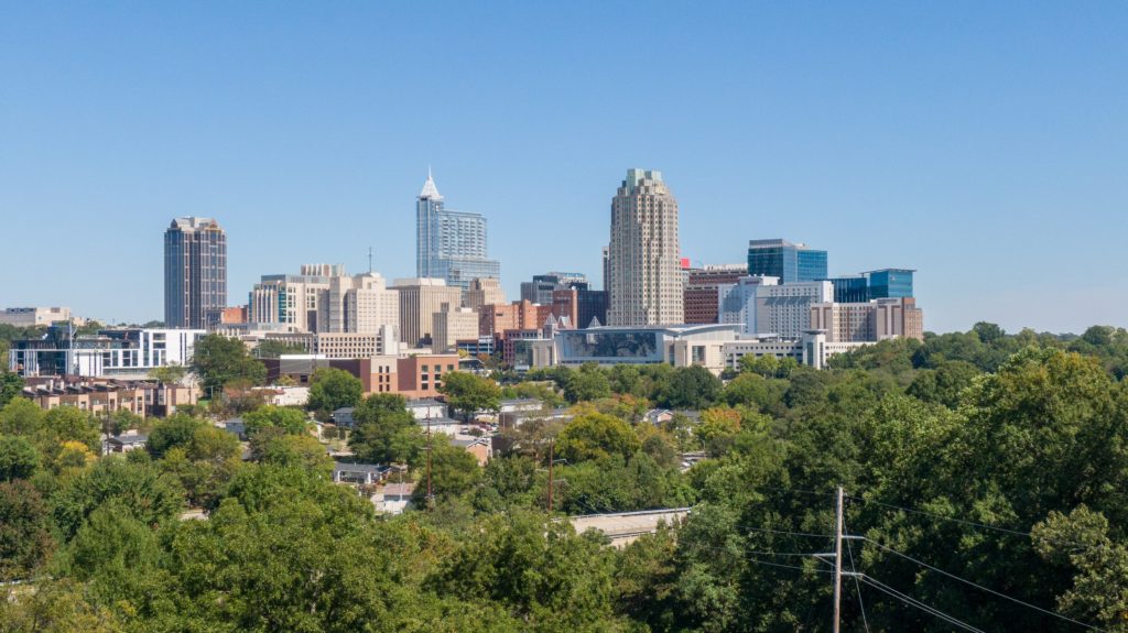 Photo of the city skyline of Raleigh, NC, at a distance.