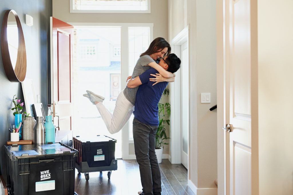 Happy young couple moving into their new home in Cary, NC; man lifting woman in a hug.
