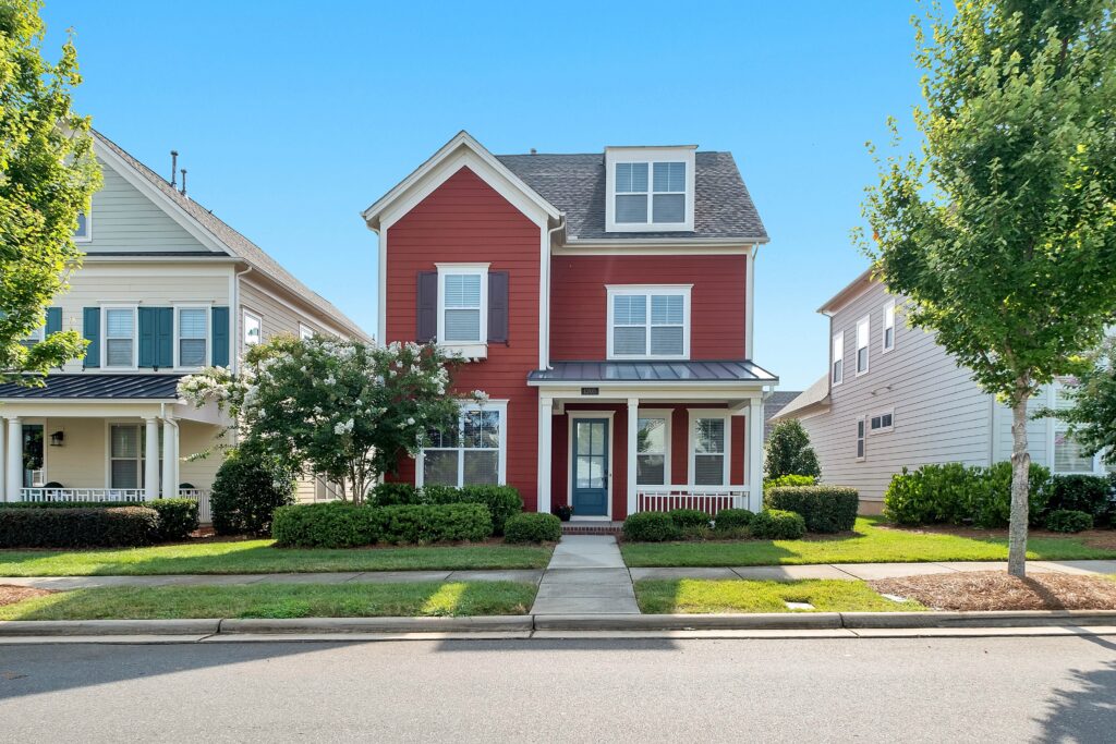 Beautiful two-story red home with small front porch on residential street in a North Carolina neighborhood.